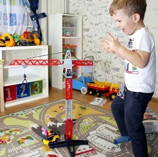 Ein Kind spielt in einem Kinderzimmer auf einem Spielteppich mit Straßen. - Ein Kind spielt in einem Kinderzimmer auf einem Spielteppich mit Straßen.