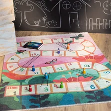 Kinderteppich - Kinderspielteppich mit einem Würfelspiel Motiv, liegt auf dem Boden.